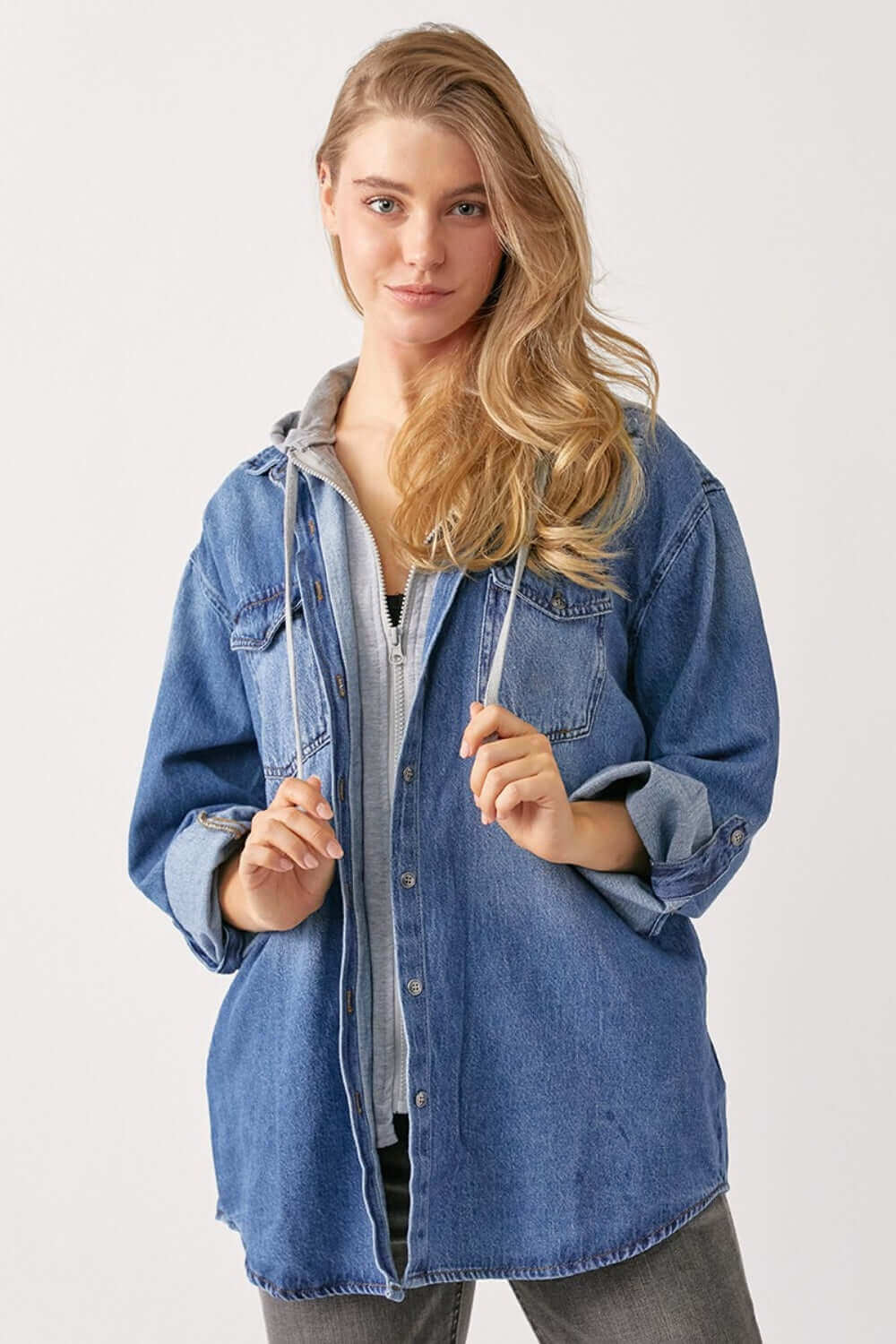 Woman wearing lightweight zip up hooded denim shirt by Risen Jeans. Casual oversized design, perfect for pairing with leggings, joggers, or denim.