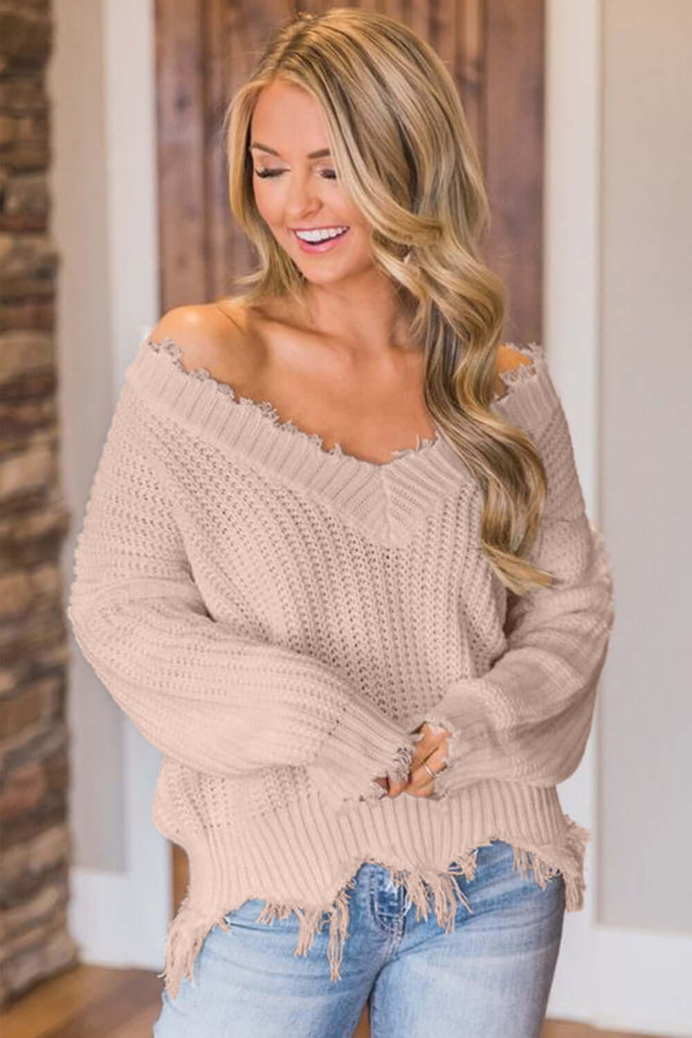 Woman wearing Bella Road frayed hem dropped shoulder sweater, showing a playful and casual fashion style.