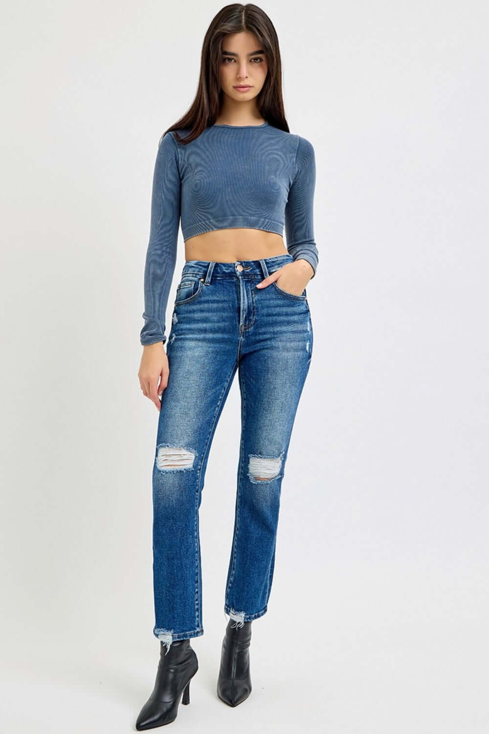 Trendy high rise distressed crop jeans paired with a chic blue top and black boots for an edgy fashion statement.