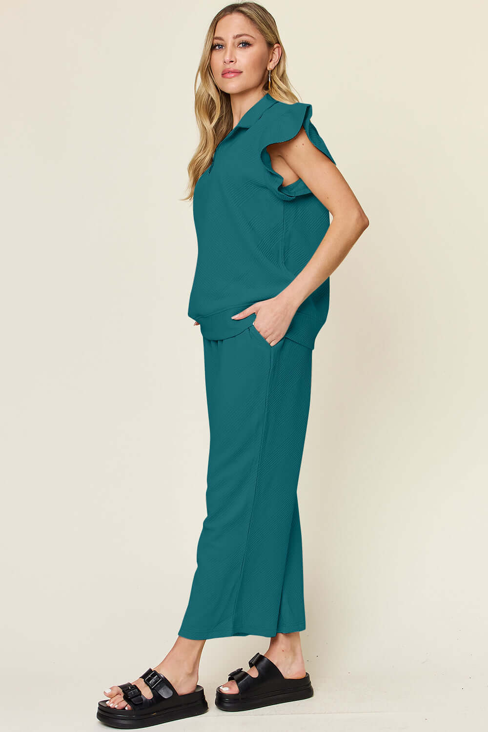 Woman wearing a teal texture ruffle short sleeve top and drawstring wide leg pants set, with pockets, slightly stretchy fabric.