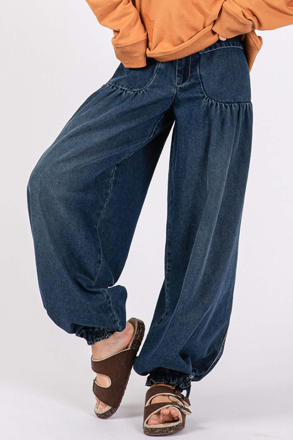 Mid-rise cargo jeans with cinch-tie banded ankles and dropped front patch pockets paired with brown sandals.