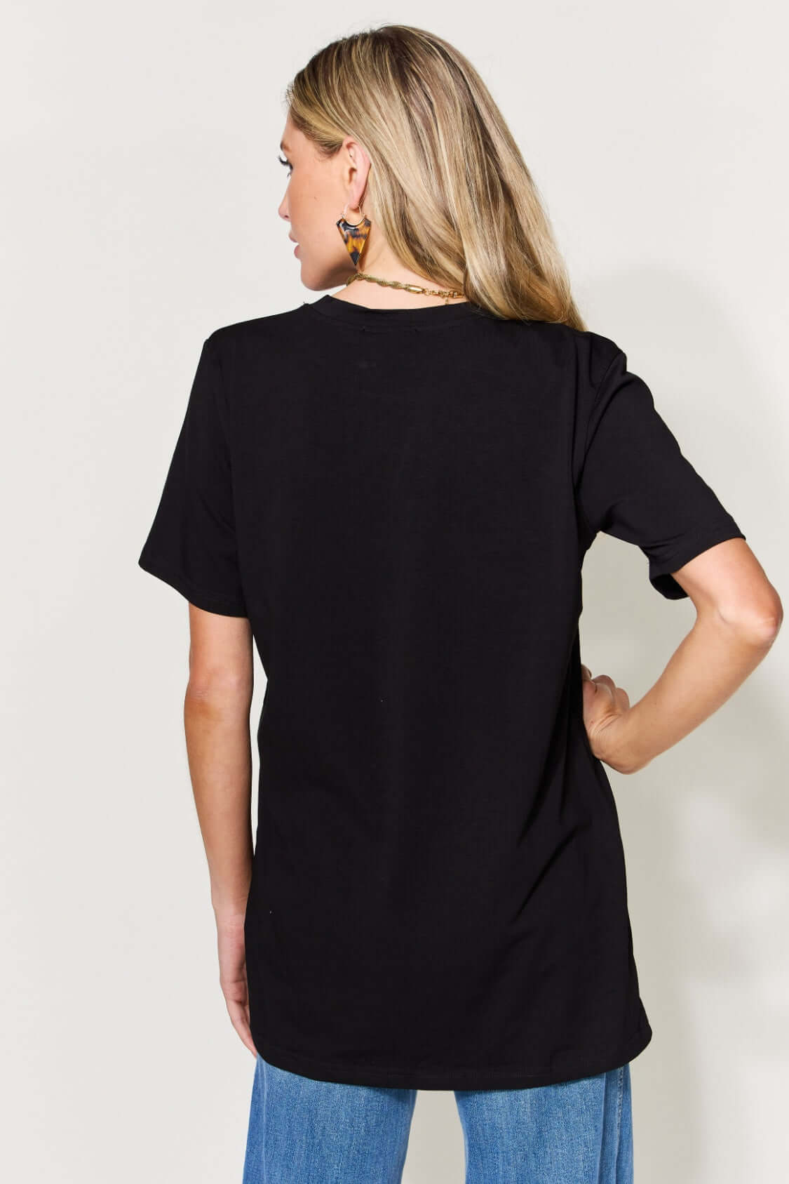 Back view of woman wearing black MAMA round neck short sleeve T-shirt, paired with blue jeans.