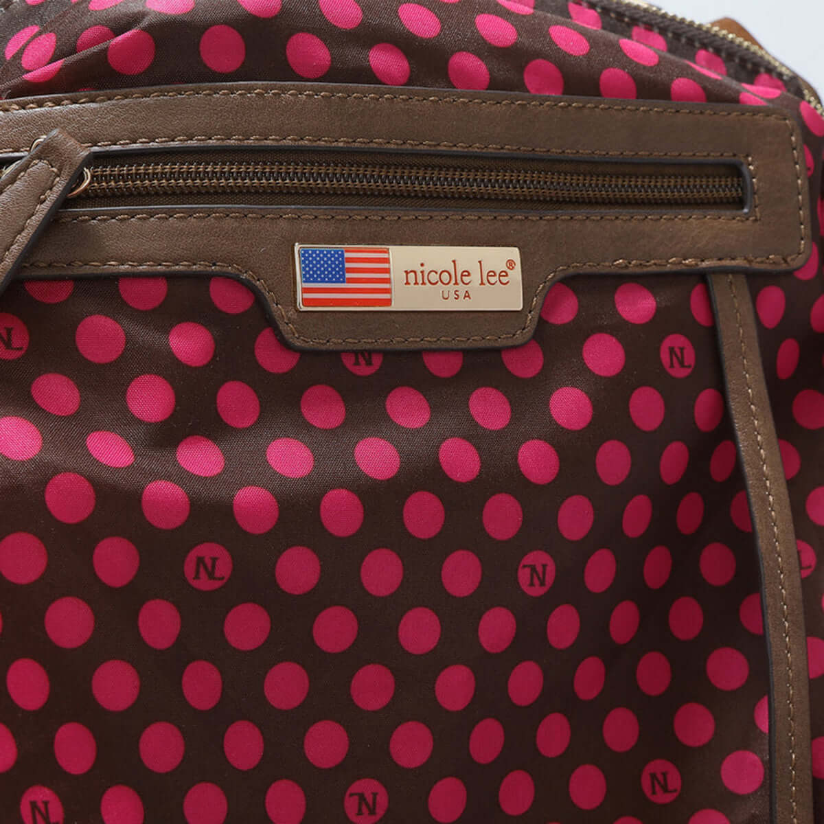 Close-up of Nicole Lee USA crossbody bag with pink polka dot interior and front zip pocket.