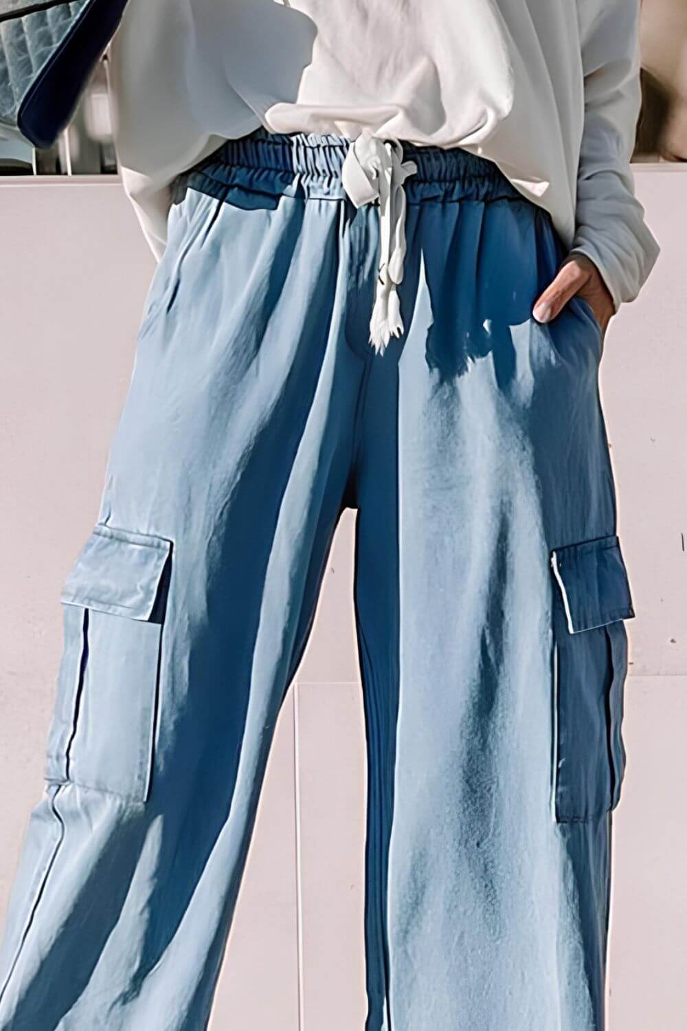 Light wash wide leg cargo jeans with drawstring waist, perfect for a stylish casual look.