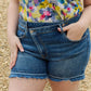 Woman wearing Maya Mid Rise Asymmetrical Shorts by Risen Jeans for a casual and comfortable look.