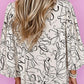 Woman wearing Bella Road printed round neck three-quarter sleeve blouse with abstract design, viewed from the back.