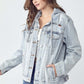 Young woman wearing a distressed drawstring hooded denim jacket, showcasing a casual and stylish look.