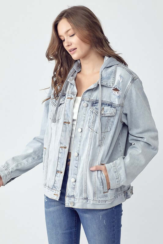 Young woman wearing a distressed drawstring hooded denim jacket, showcasing a casual and stylish look.