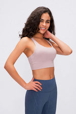 Model showcasing the Millennia Double X Sports Bra in basic colors, featuring a stylish design and supportive fit for workouts.