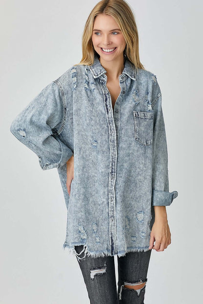 Woman wearing distressed raw hem denim shirt by Risen Jeans, exuding a casual and edgy look with frayed edges and rugged details