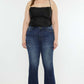 Woman wearing Kancan mid-rise slim flare jeans in dark stone wash, showcasing a flattering silhouette and versatile style.