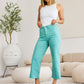 Woman wearing Tummy Control High Waist Raw Hem Jeans in teal, posing indoors with a trendy and stylish look.