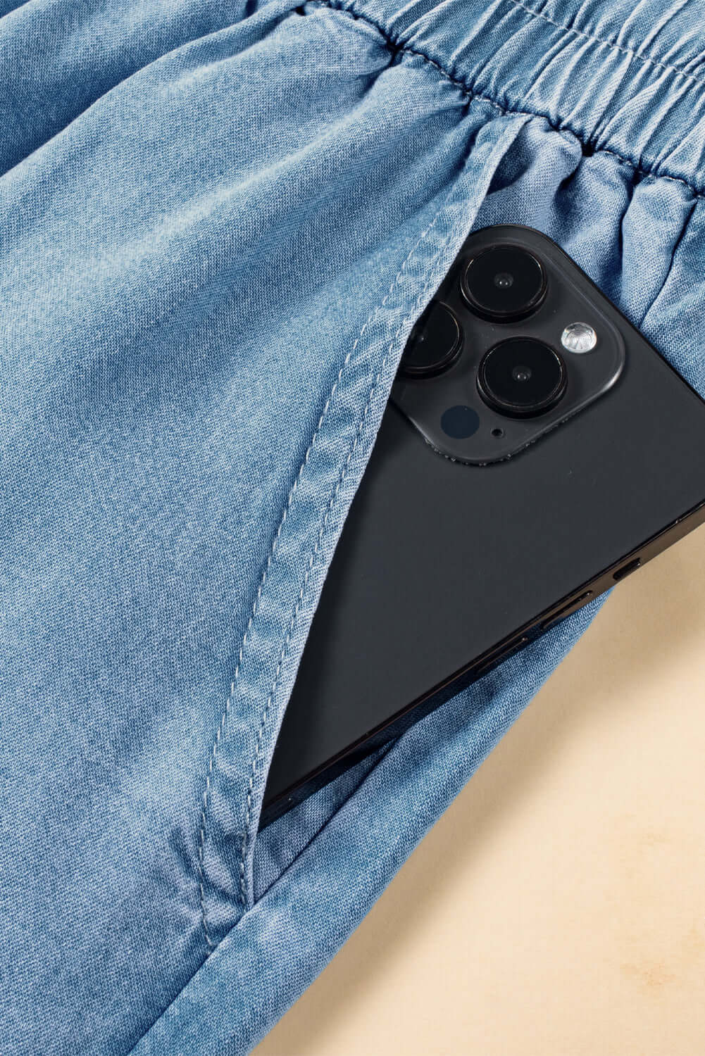 Close-up of light wash cargo pocket jeans with a smartphone tucked into the pocket, showcasing practical style.