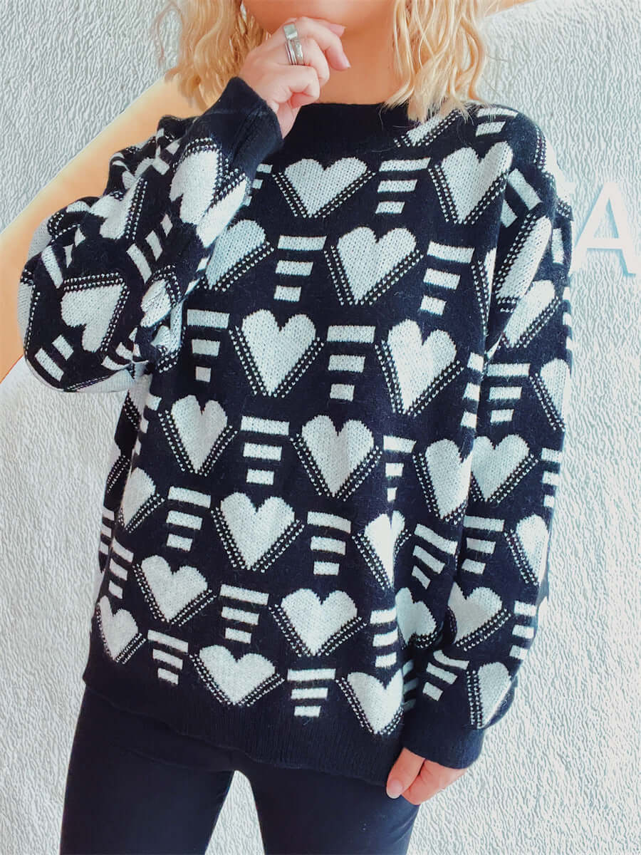 Woman wearing Bella Road Heart Contrast Long Sleeve Dropped Shoulder Sweater with black background and white hearts design.