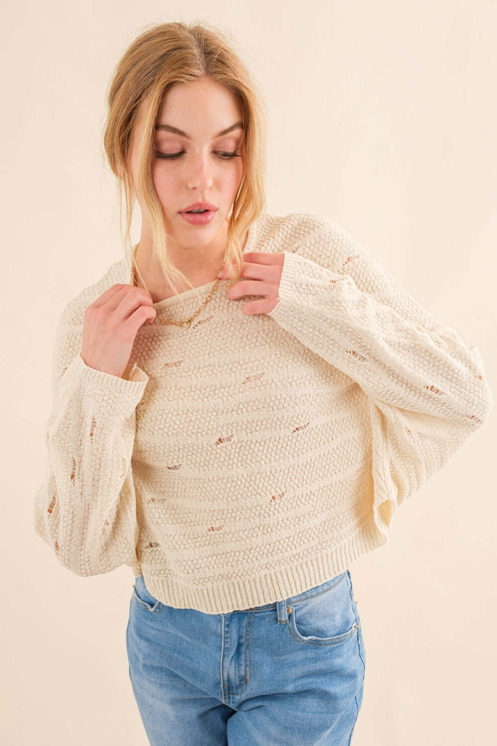 Woman wearing cozy Dolman Sleeves Sweater in cream, paired with blue jeans. Perfect for cooler months, offering a relaxed, trendy, and versatile look.