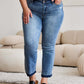 Woman wearing Judy Blue release hem cropped bootcut jeans with sandals in living room.