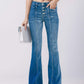 Woman wearing button fly bootcut jeans with pockets, holding a white clutch, showcasing slightly stretchy denim fabric and a modern fit.