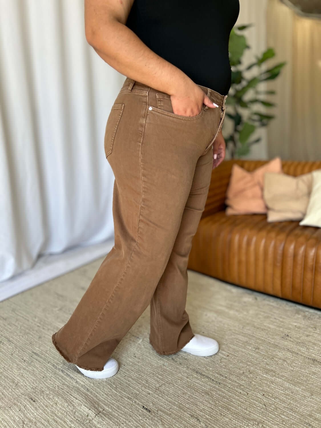 Model wearing RFM Full Size High Rise Garment Dye Wide Leg Jeans in rich brown color, side view showing relaxed fit and high-waist design