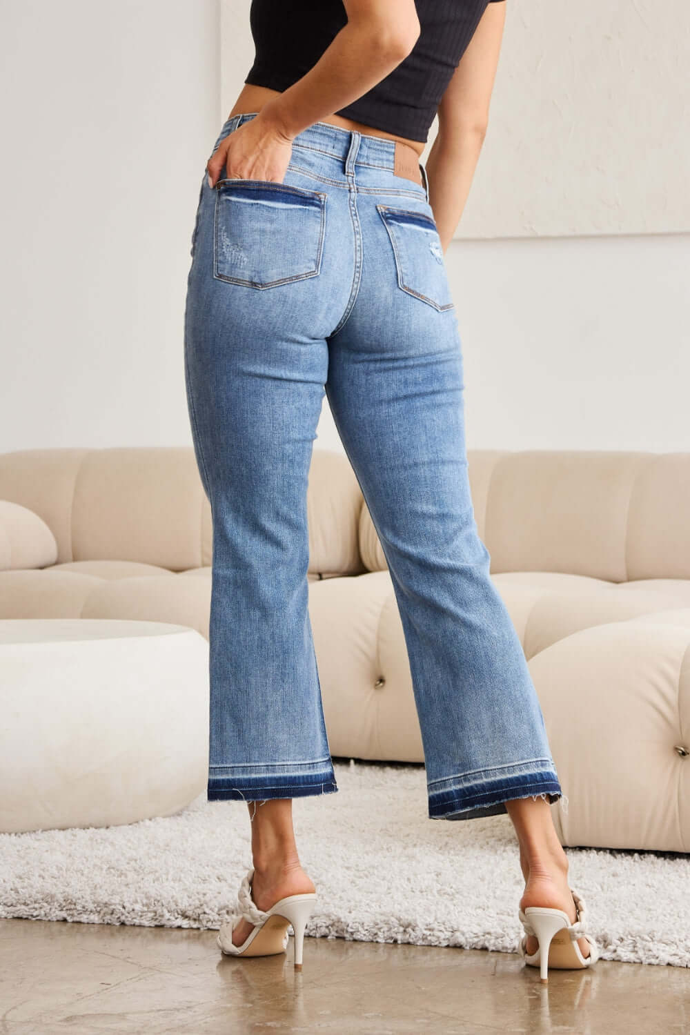 Woman wearing Judy Blue release hem cropped bootcut jeans with heels, showcasing modern bootcut silhouette and stylish cropped length.