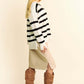 Model showcasing a chic Davi & Dani high-low striped sweater paired with a stylish skirt and knee-high boots.