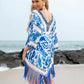 Woman wearing a blue cutout V-neck three-quarter sleeve cover-up with tassels on the beach