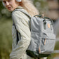 Woman wearing a Himawari waterproof canvas backpack with side pockets while listening to music outdoors.