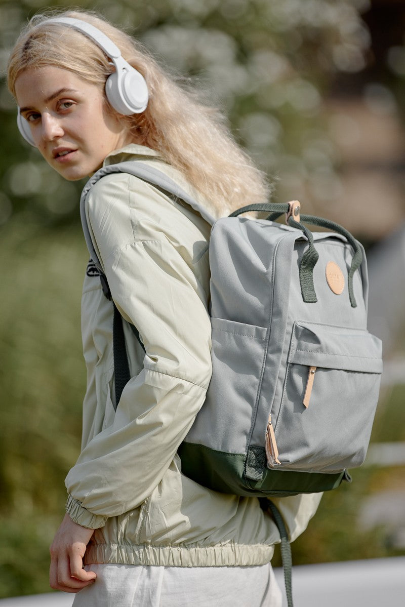 Woman wearing a Himawari waterproof canvas backpack with side pockets while listening to music outdoors.