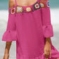 Woman wearing a crochet cold shoulder three-quarter sleeve cover up in bright pink, with colorful ruffled details, at the beach