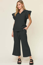 Woman wearing black Texture Ruffle Short Sleeve Top and Drawstring Wide Leg Pants Set with pockets, slightly stretchy material.