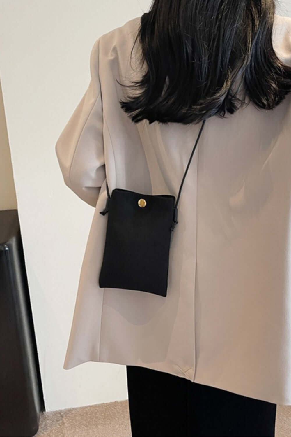 Woman wearing Bella Road Suede Snap Down Crossbody Bag in black with snap-down design and crossbody strap for hands-free convenience.