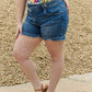 Woman wearing Maya Mid Rise Asymmetrical Shorts by Risen Jeans, flaunting a relaxed fit for all-day comfort and style.