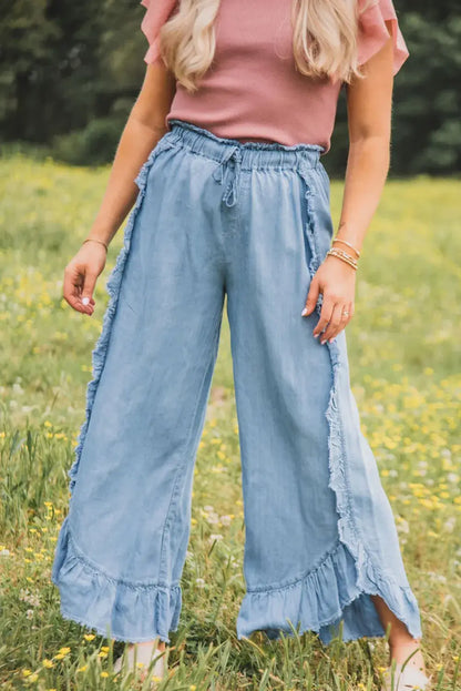 Woman wearing Bella Road Raw Hem Wide Leg Jeans in a field, showcasing trendy raw hem and flattering wide leg design.