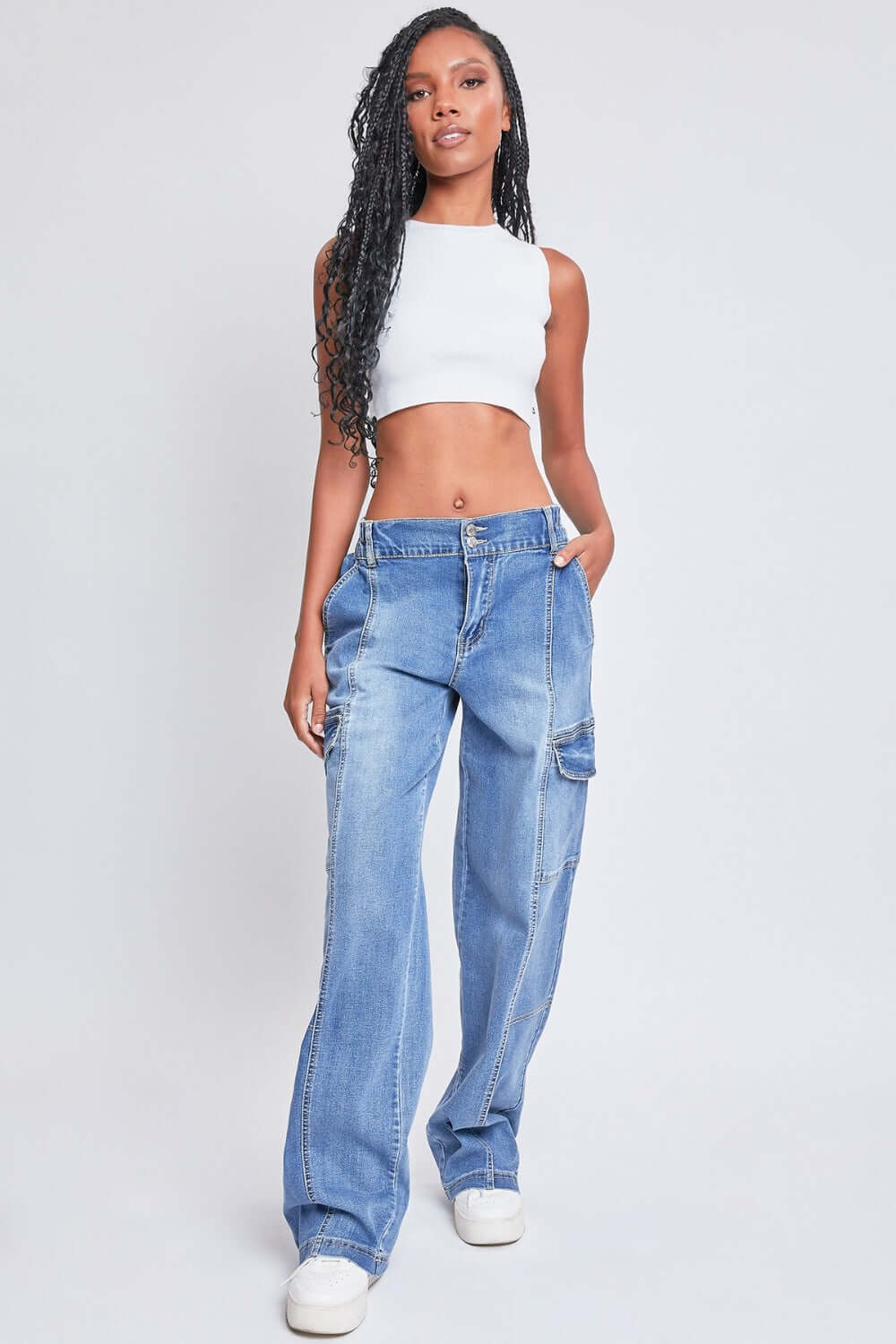 Trendy woman wearing YMI Jeans high-rise straight leg cargo jeans with comfy stretch denim and front seams, paired with a white crop top.