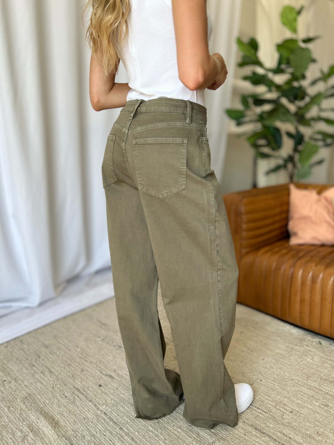 Woman wearing RFM Full Size High Rise Garment Dye Wide Leg Jeans in olive green, showcasing back pockets and wide-leg silhouette.