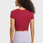 Back view of woman wearing Millennia Round Neck Short Sleeve Cropped Sports T-Shirt in burgundy with yoga leggings.