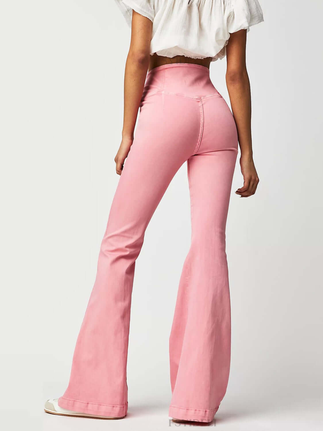 Woman wearing pink asymmetric waist flare jeans showing back view and white top