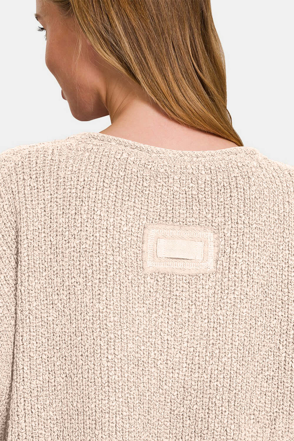 Back view of woman wearing a beige short sleeve side slit sweater with soft knit fabric, showcasing detailed texture and stitching.