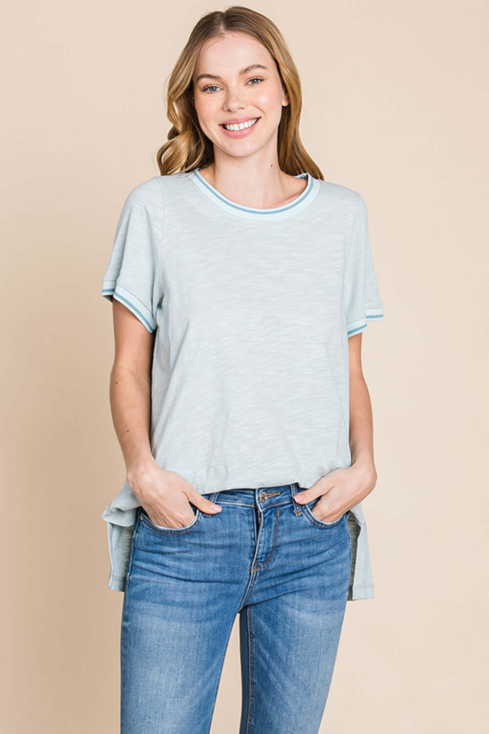 Woman wearing contrast trim short sleeve slit T-shirt in light blue with jeans, showcasing modern and stylish casual wear.