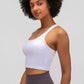 Woman showcasing the Millennia Racerback Sports Bra in white, perfect for yoga and workouts with a sleek, sporty design.