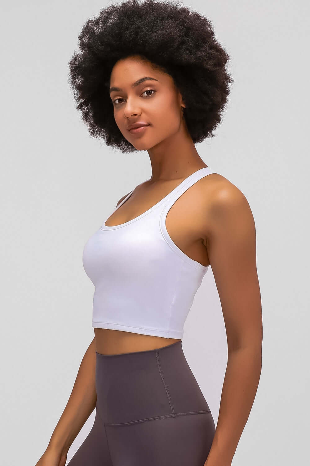 Woman showcasing the Millennia Racerback Sports Bra in white, perfect for yoga and workouts with a sleek, sporty design.