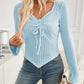 Woman wearing Bella Road ribbed drawstring long sleeve T-shirt in light blue with jeans, showcasing stylish and comfortable fashion.