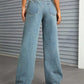 Woman wearing Bella Road Distressed Wide Leg Jeans with Pockets standing in front of a corrugated metal wall.