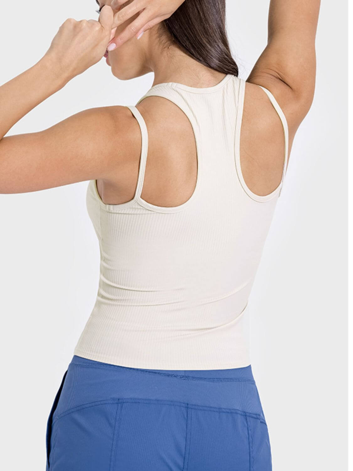 Back view of a stylish beige racerback tank top, showcasing its cutout design and comfortable fit for active wear.