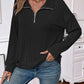 Woman wearing a black striped half zip long sleeve t-shirt paired with blue jeans.