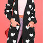 Woman wearing Bella Road Heart Open Front Long Sleeve Cardigan with white hearts design and pockets