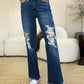 Full Size Mid Rise Distressed Raw Hem Judy Blue Jeans styled with white sneakers in a casual room setting