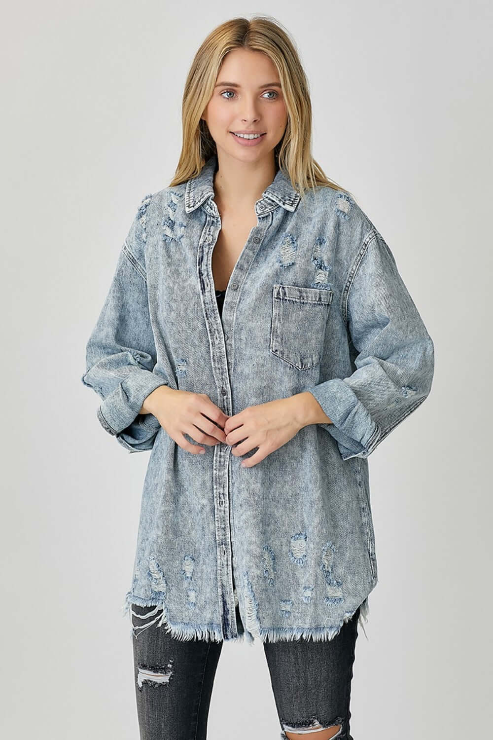 Woman wearing a Distressed Raw Hem Denim Shirt by Risen Jeans with frayed edges, exuding a casual and edgy laid-back vibe.