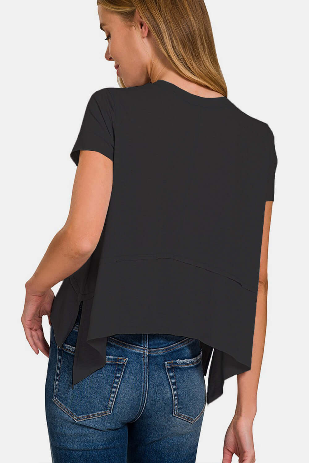 Woman wearing black slit high-low round neck t-shirt with blue jeans, modern trendy fashion.