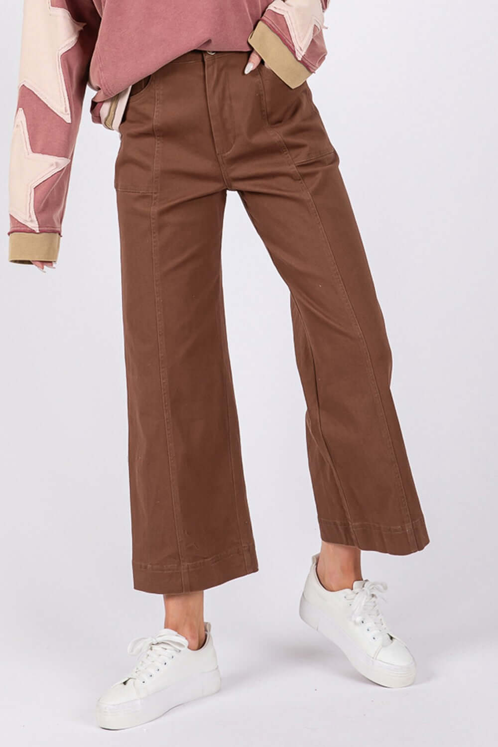 Woman wearing brown wide leg cropped pants with white sneakers, featuring front pockets and a comfortable fit.