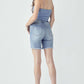 High Rise Distressed Denim Shorts by Risen Jeans with raw hem and pocketed design, modeled from behind.